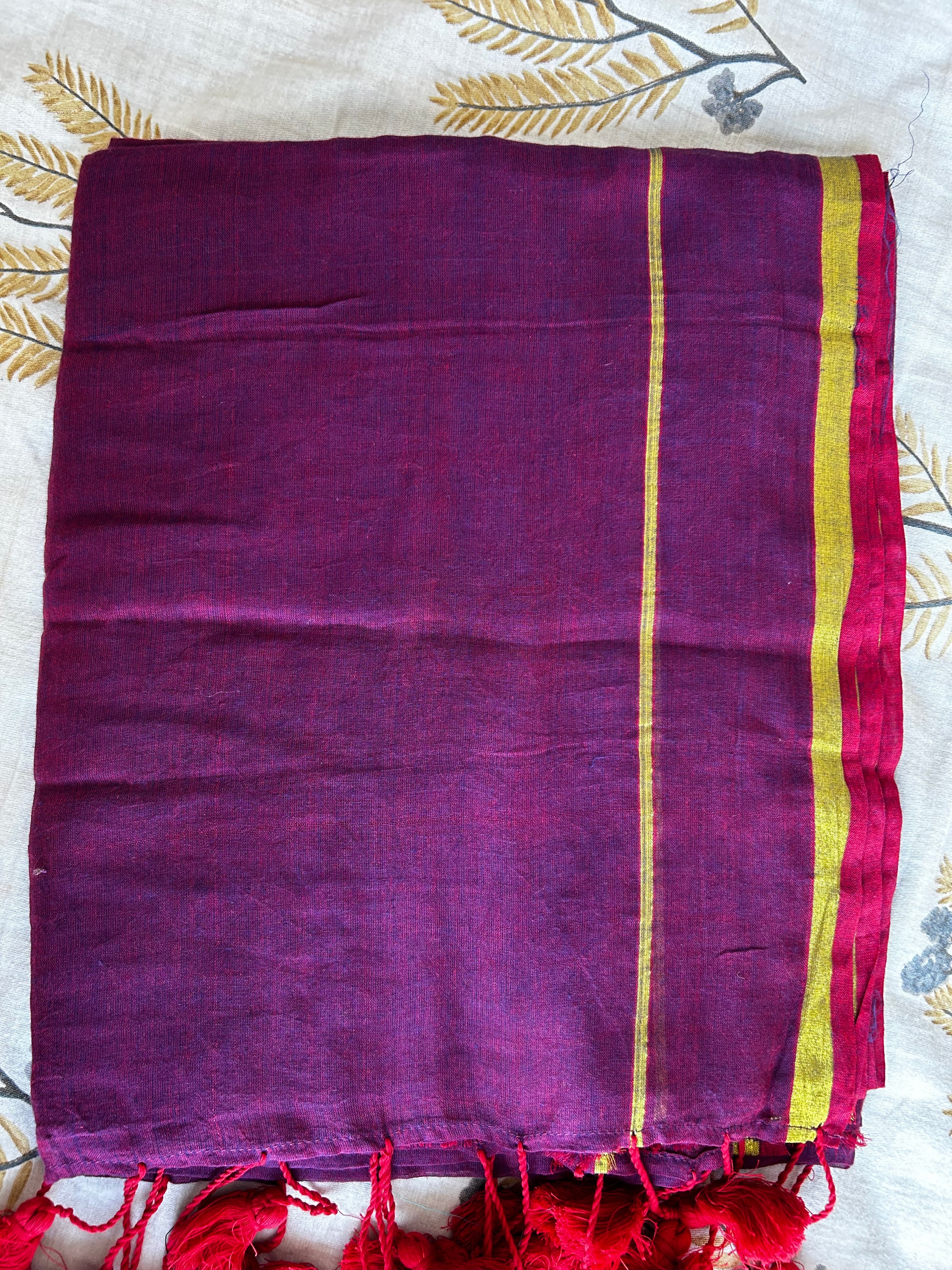 Purple fabric with gold stripes and red tassels on a patterned background